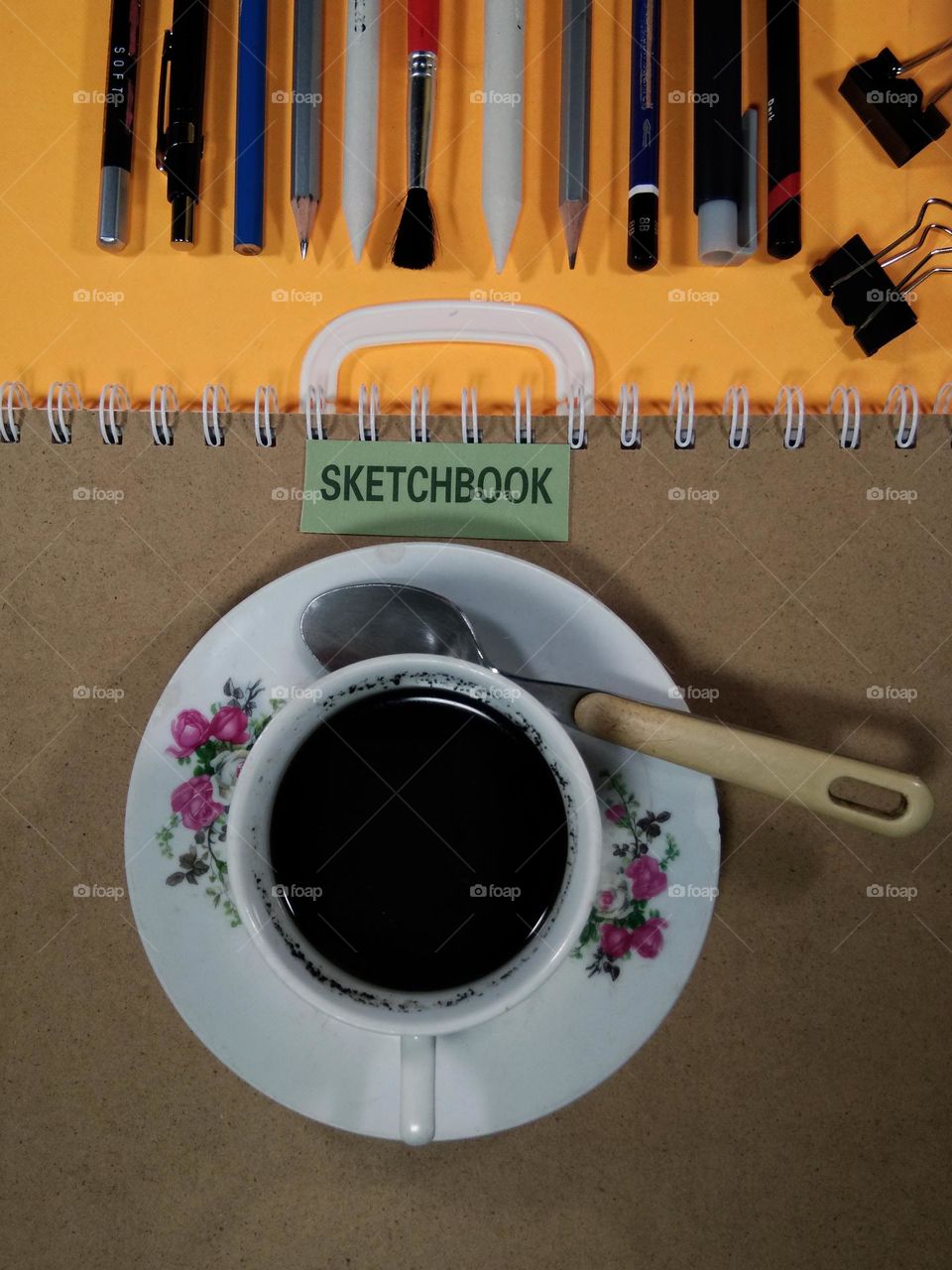 pencils, sketchbook and other pencil drawings equipment on the table.  and black coffee,  the mood booster when creating