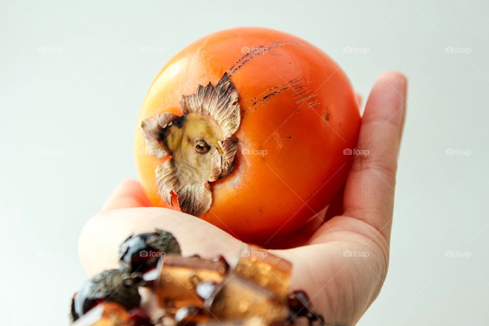 Close-up of person hand holding persimmon fruit