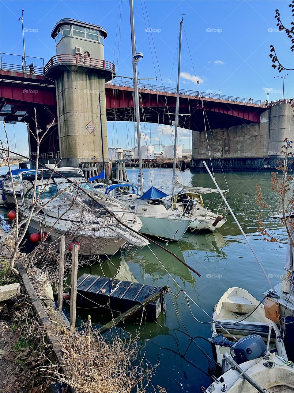 This is picturesque “Newtown Creek” by the “Pulaski Bridge” in LIC, Queens with various different kinds of boats tied to a narrow strip of land that holds several long wooden planks with hooks and similar structures. 2023. Hypnotic Productions