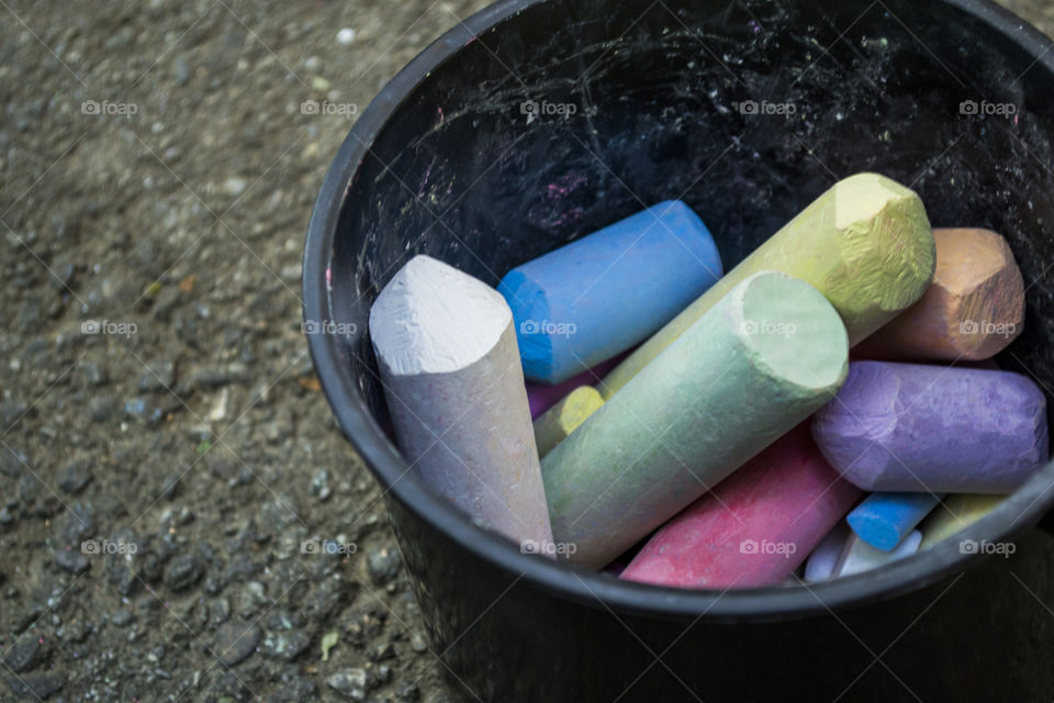 Black bucket full of colored chalk pieces