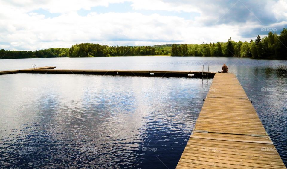 Water. A man sitting on the jetty in the lake