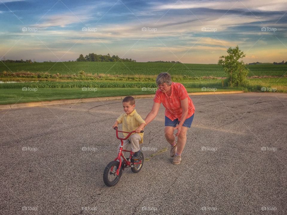 Grandmother helping her grandson to ride the bicycle