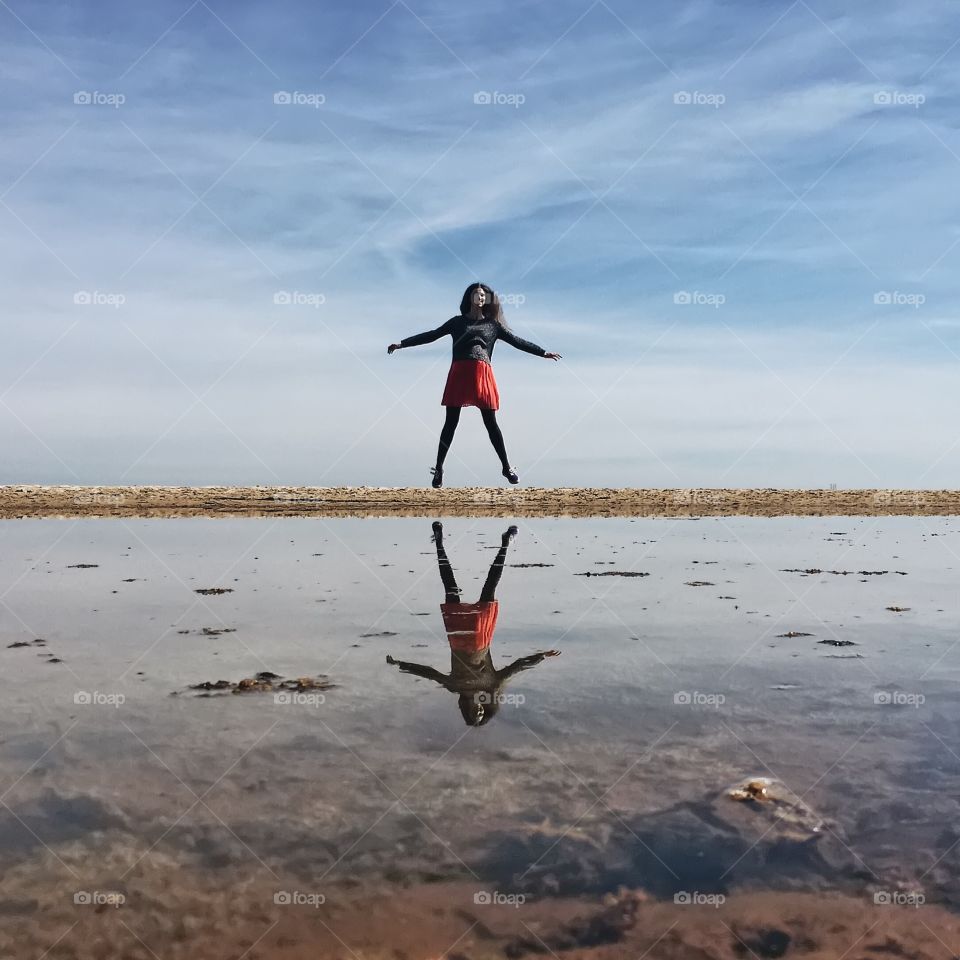 Reflection of jumping woman in lake