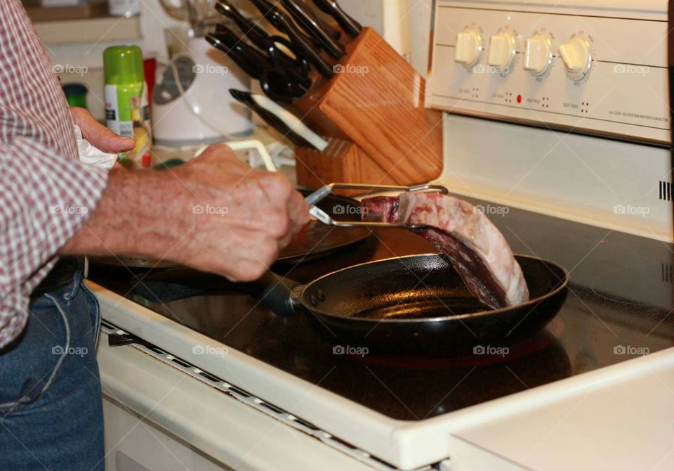 Putting the steak in the pan to sear.