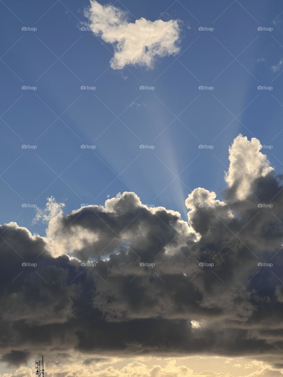 Morning sun rise behind the clouds with the sun rays reaching the blue sky 