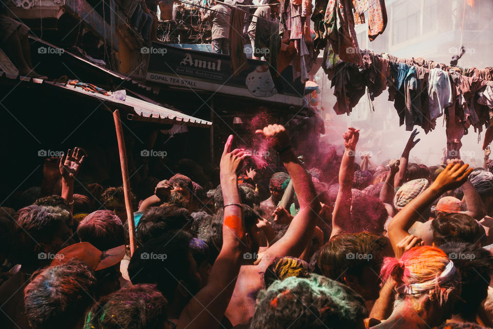 People throw orange and pink powder in a crowded square during Holi festival in Pushkar, India.