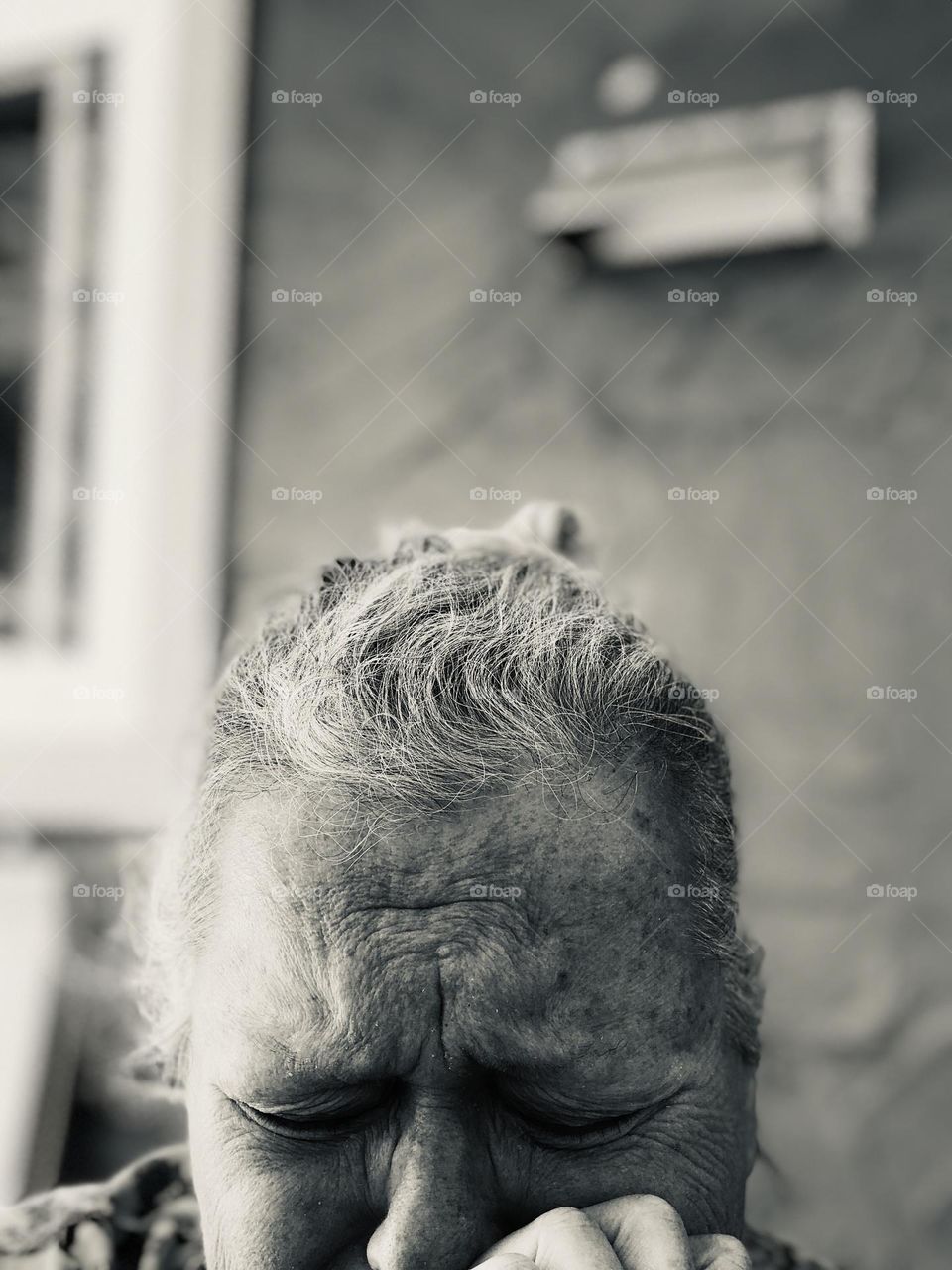 Black and white selfie of the top of a woman’s head. Her brow and eyes are deeply creased and she looks like she’s crying. Her skin is mottled and her hair is messily gathered at the top of her head. 