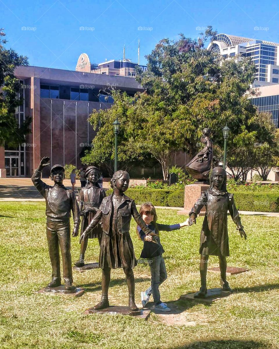 Austin Texas girl child statues Park green trees holding hands