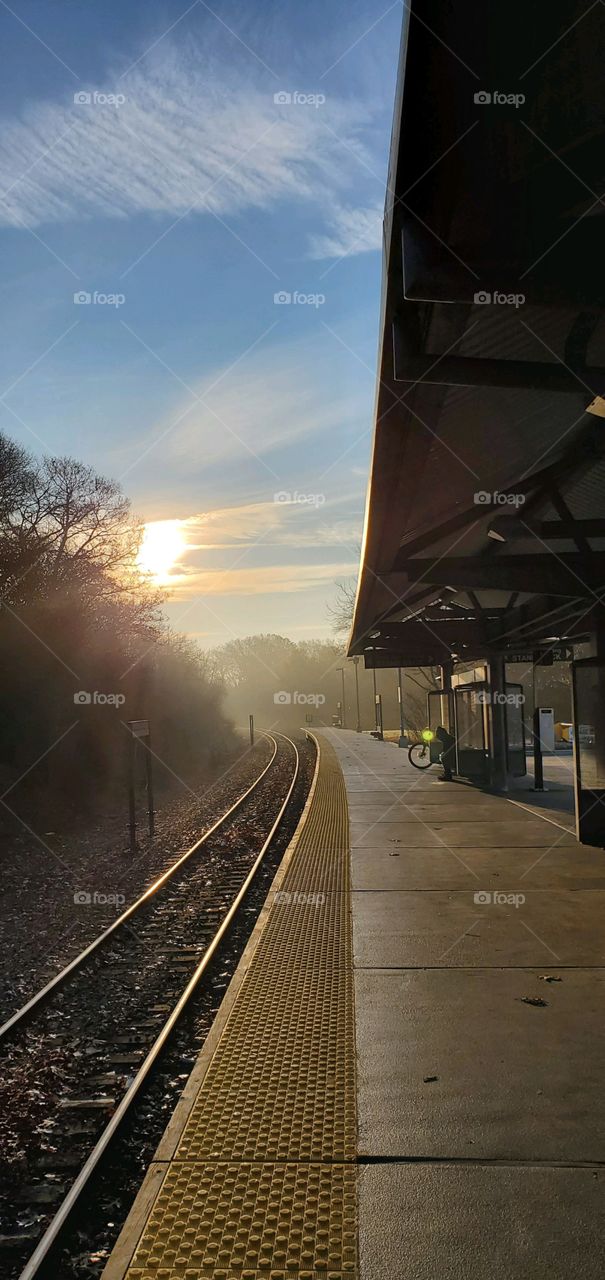Sunrise, sunset in USA! Early morning sunrise over train tracks as I stand on waiting platform commuting to the city from the suburbs.