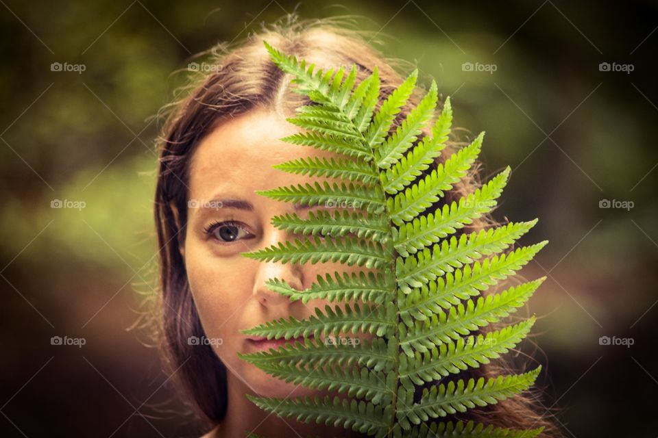 Woman holding leaf in front of her face