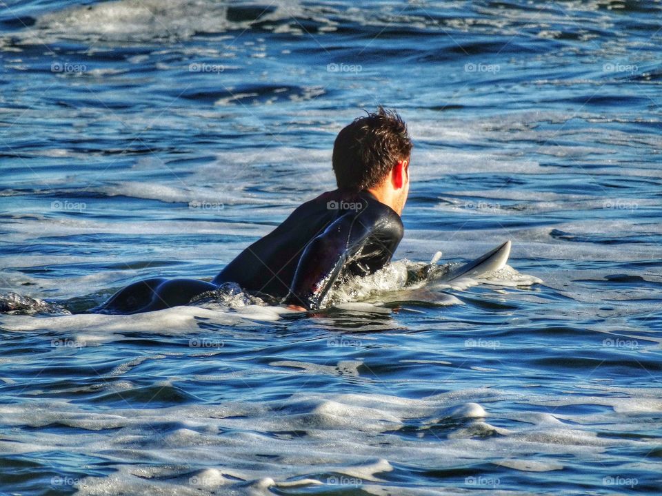 Surfer Paddling Out To The Ocean