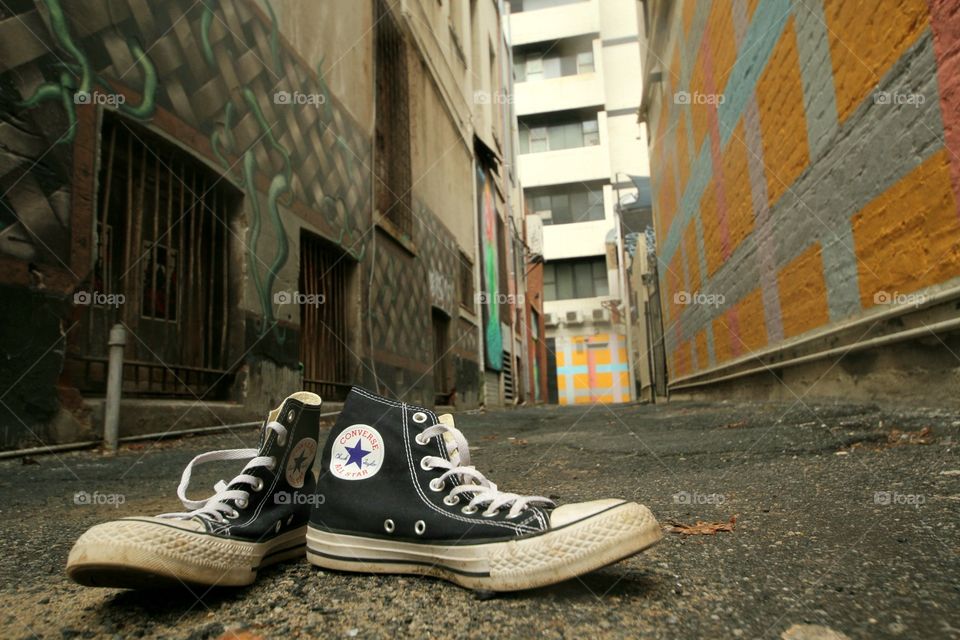 genuine original converse all-star high tops in the foreground of a back alley in Perth, Western Australia