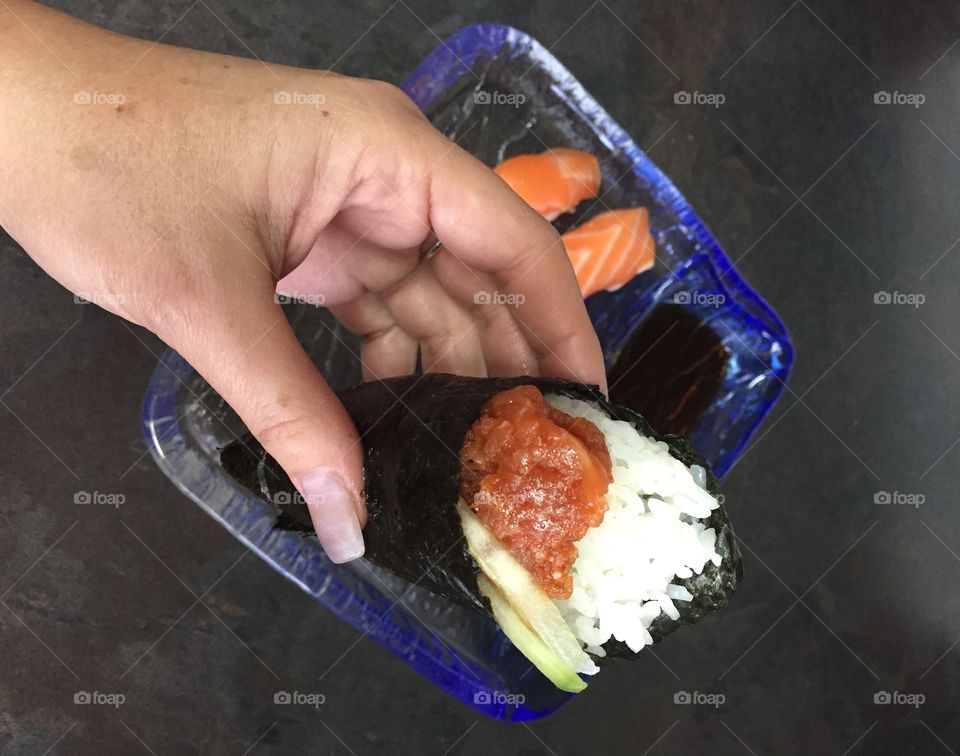 Hand holding sushi hand roll 