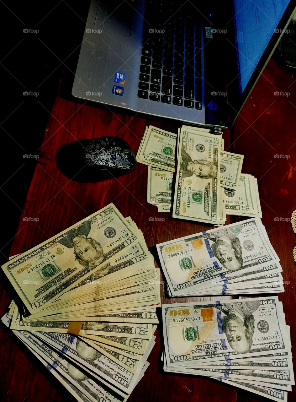 Cash U.S. paper money on desk, near computer laptop.
