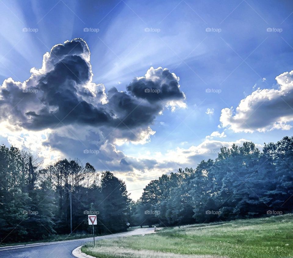 The clouds engulfing the sun leaving behind rays of light throughout the afternoon sky.