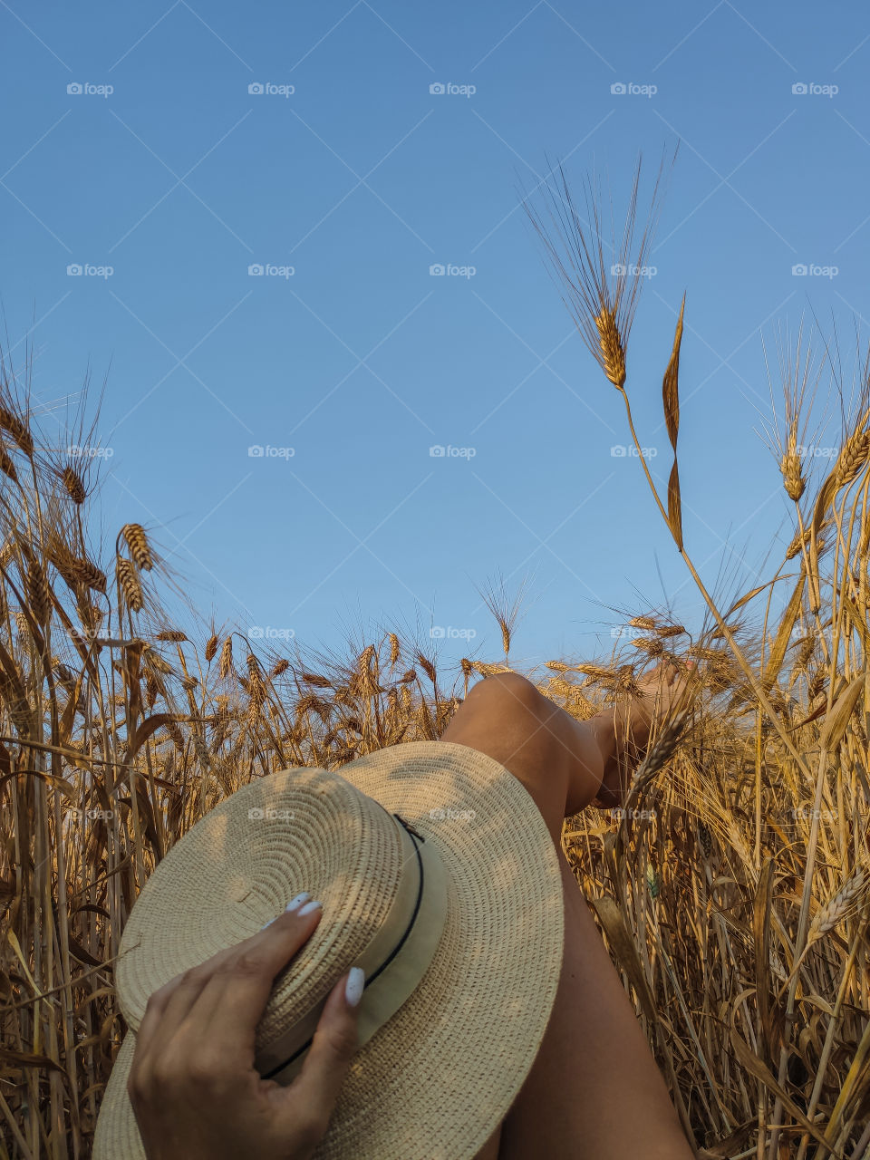 female feet and hat in a wheat field