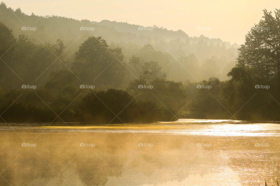 Early morning fog burns off the lake as the sun rises