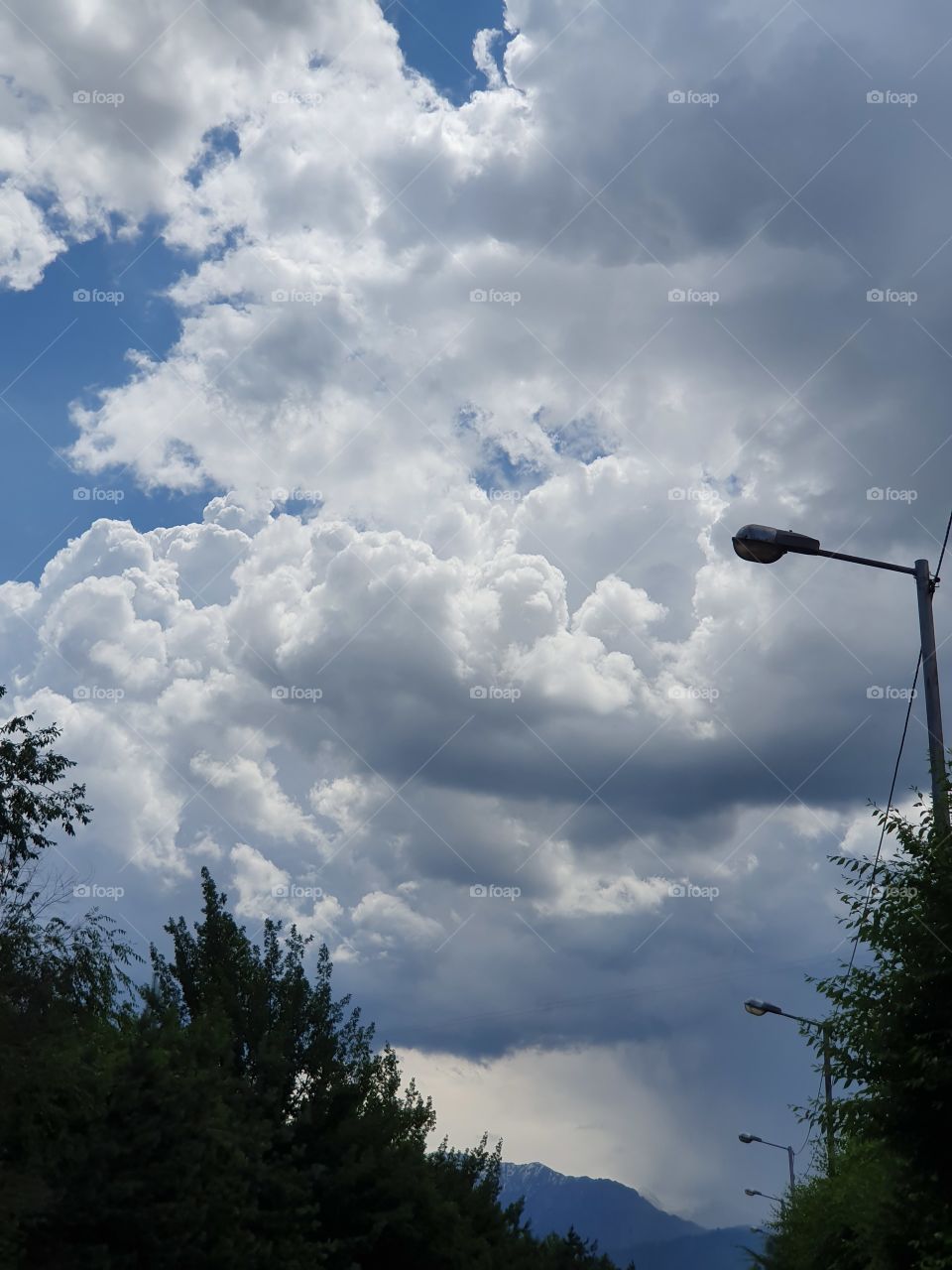 drammatic sky trees mountains and street lightning
