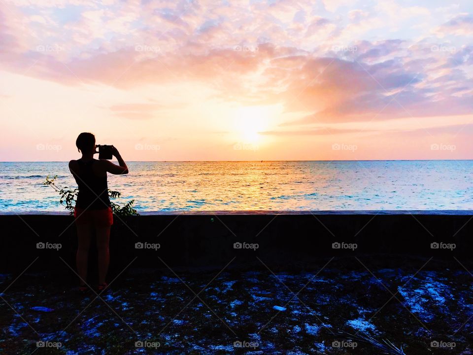 A girl taking a pic of sunset 