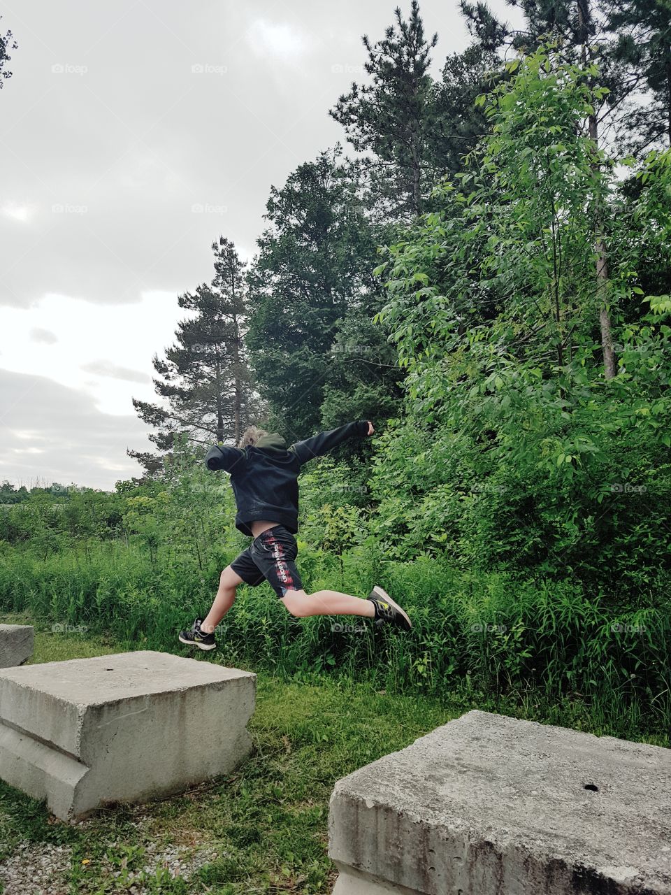 A boy jumping between cement blocks.