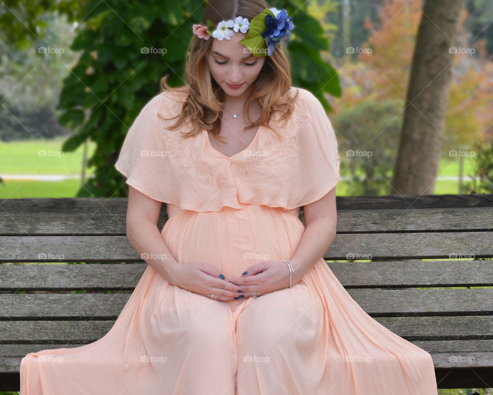 Mommy to be sitting on a park bench. 