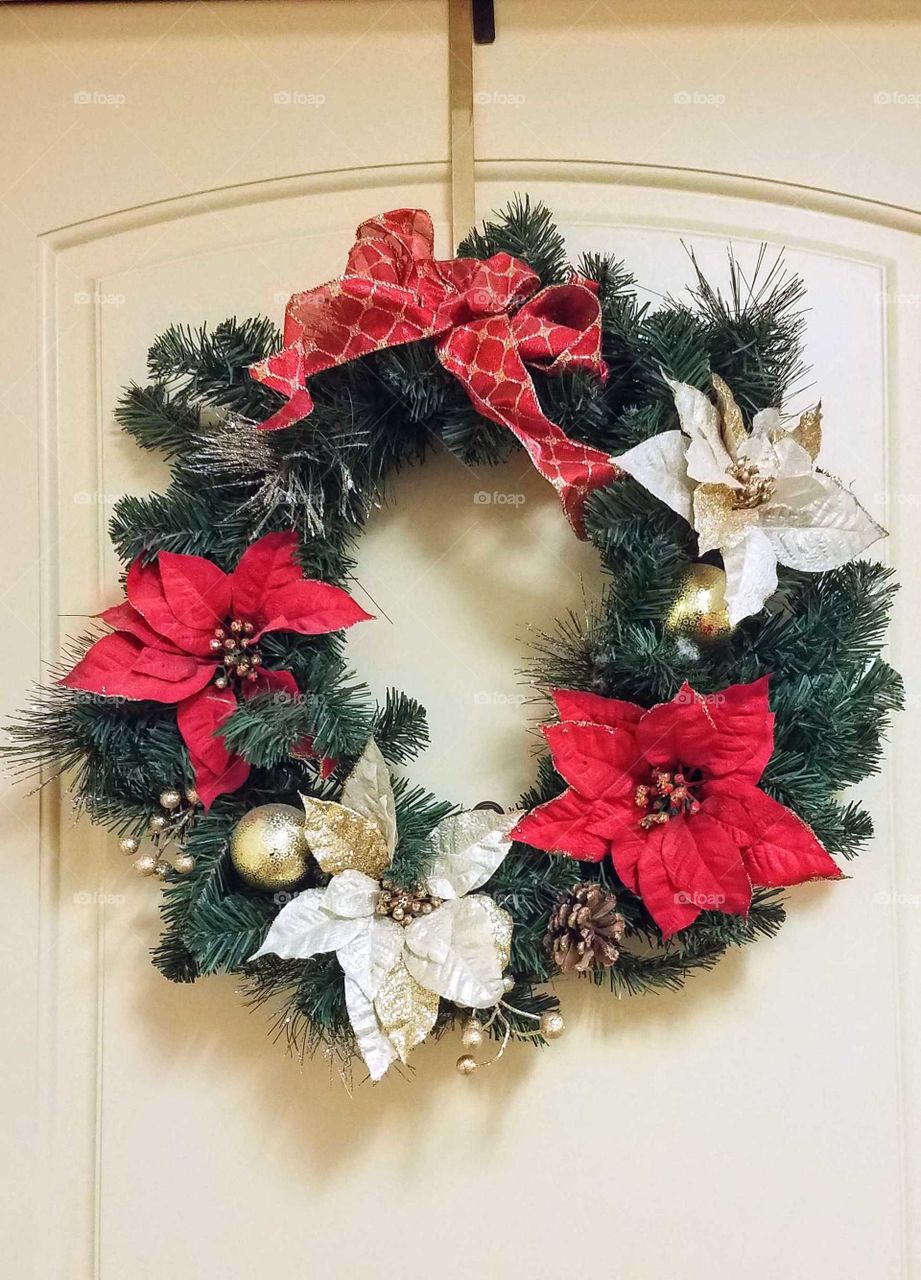 A holiday wreath of red and white poinsettias on a door