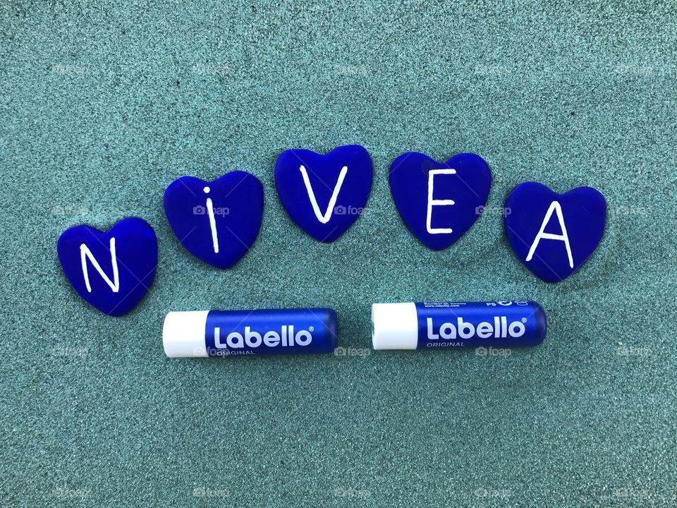 Two nivea labels with blue heart stones over the sand