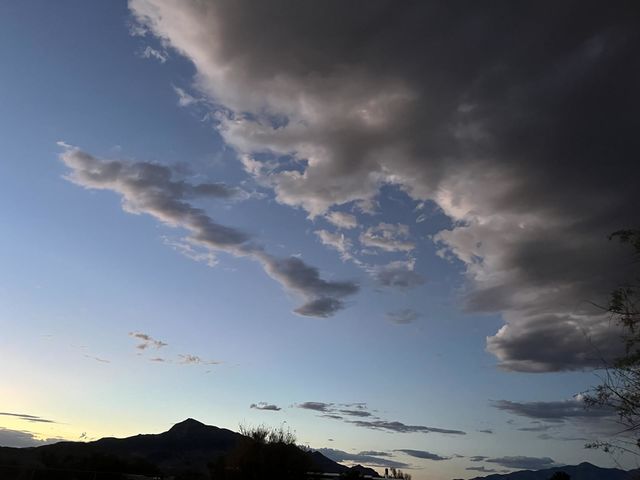 A sunset with mountains and storm clouds rolling in.