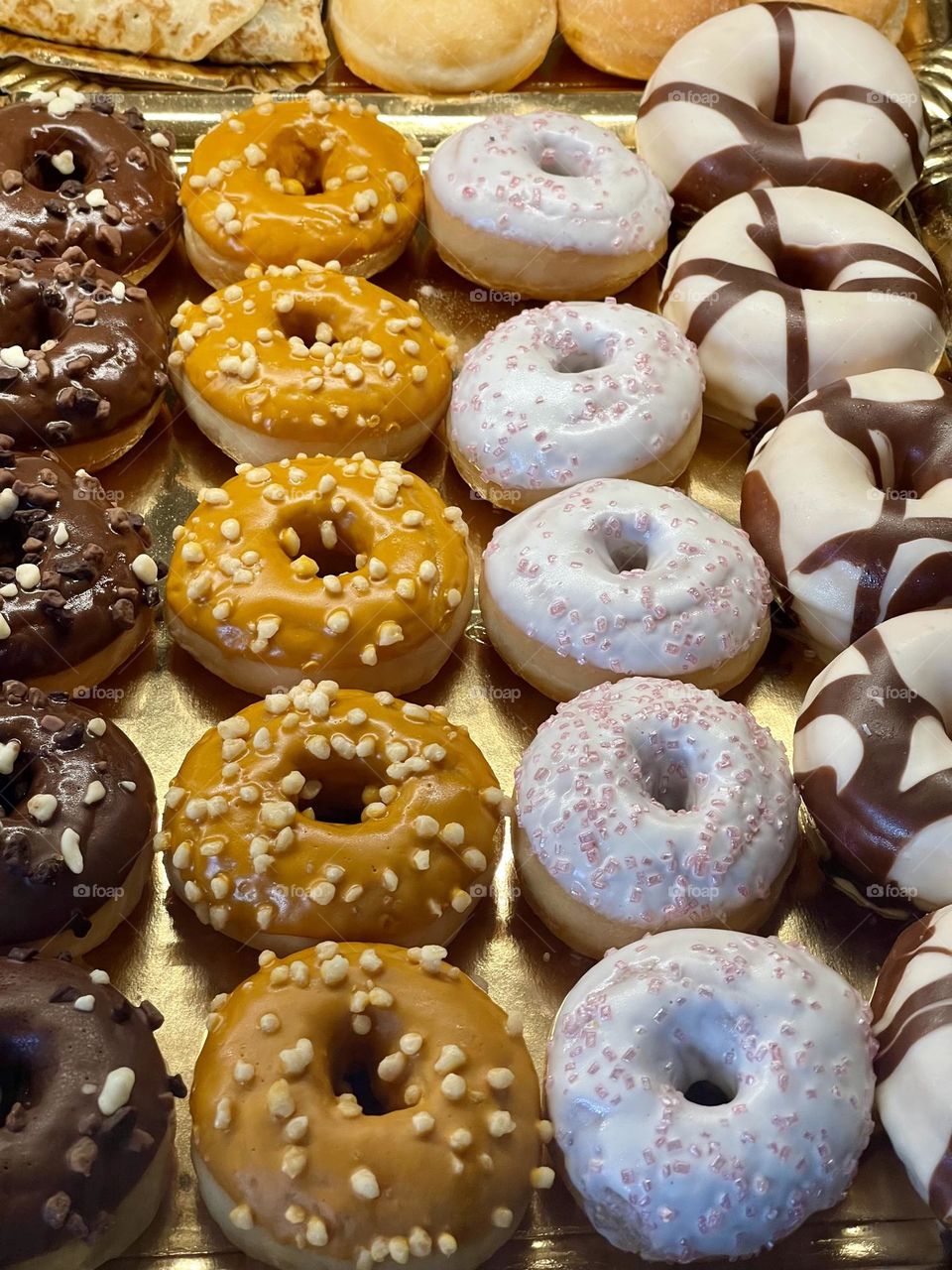 Selection of assorted colorful frosted glazed round donuts doughnuts exposed in a bakery store window 