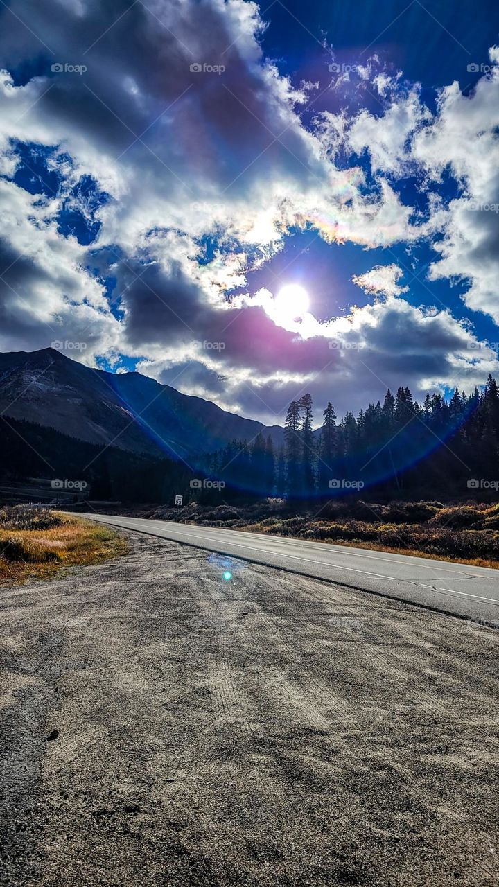 The sun breaks through the clouds and lights the highway home through the Colorado Rocky Mountains near Leadville Colorado.