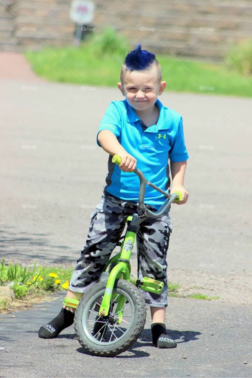 My adorable little blue haired boy getting ready to ride his bicycle in our driveway. 