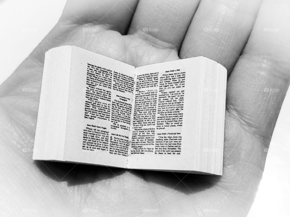 Black and white photo of a hand holding a miniature book