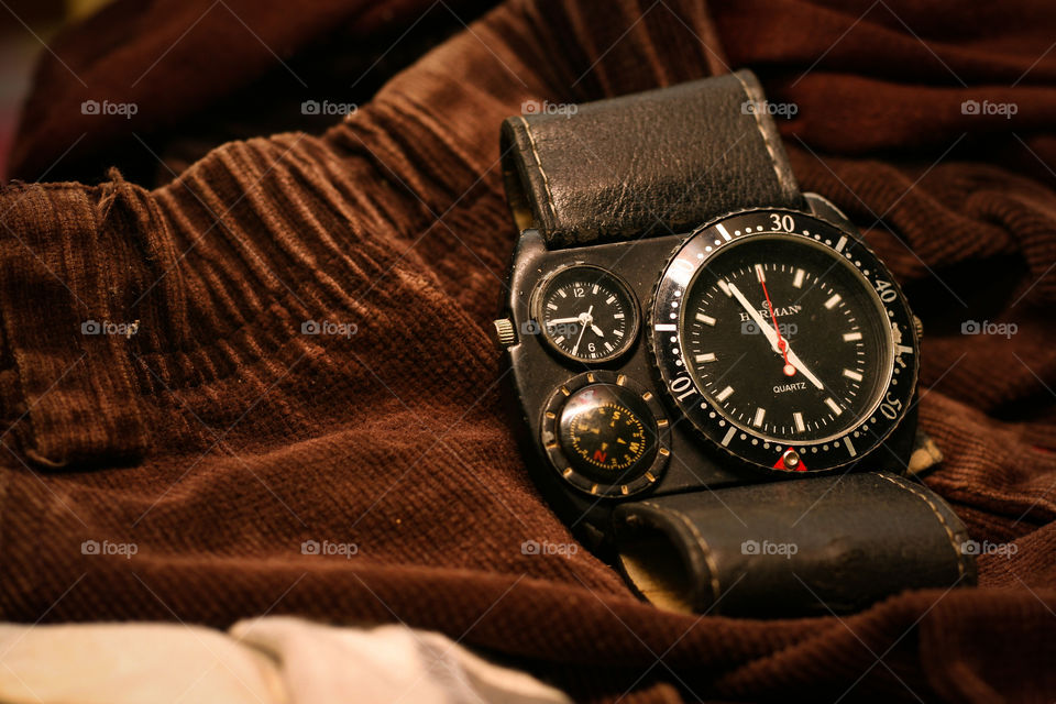 A black wrist watch on a brown clothe