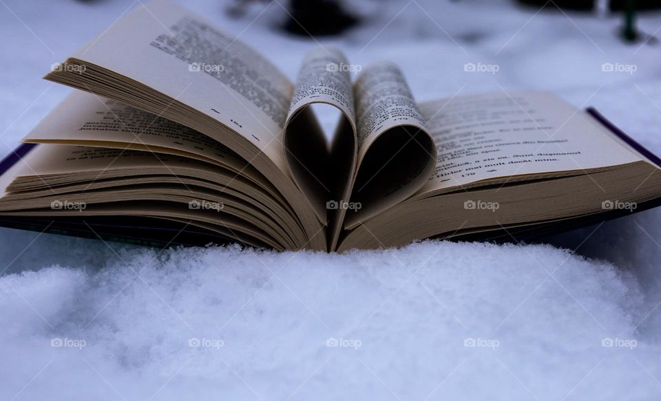 This picture represents a heart from the pages of a book placed on the pristine snow.