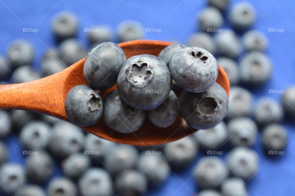 blueberries and wooden spoon top view blue background