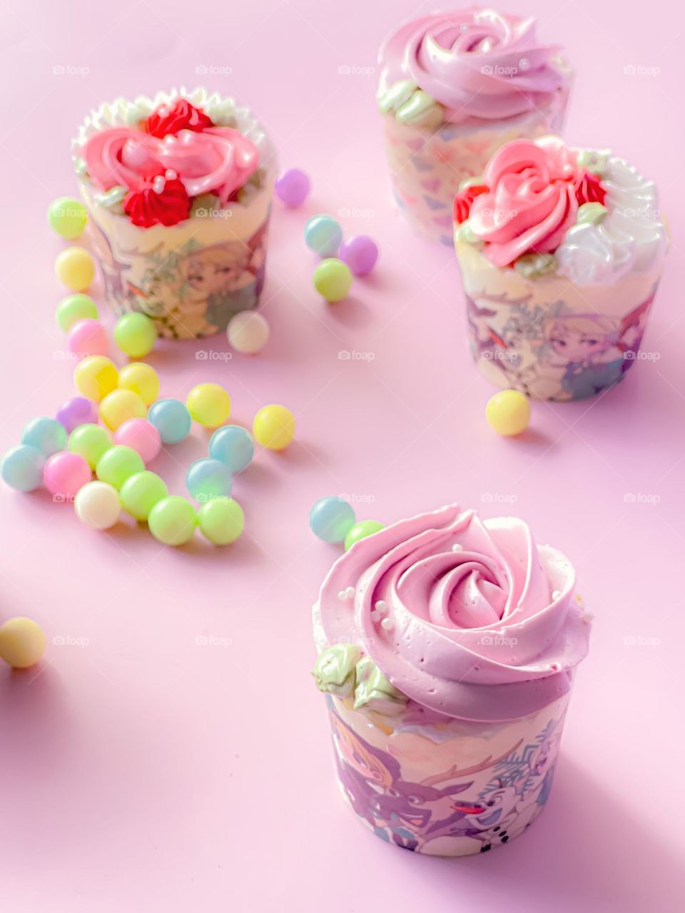 Beautiful pink cupcakes in close up view and some colouful candies on the table