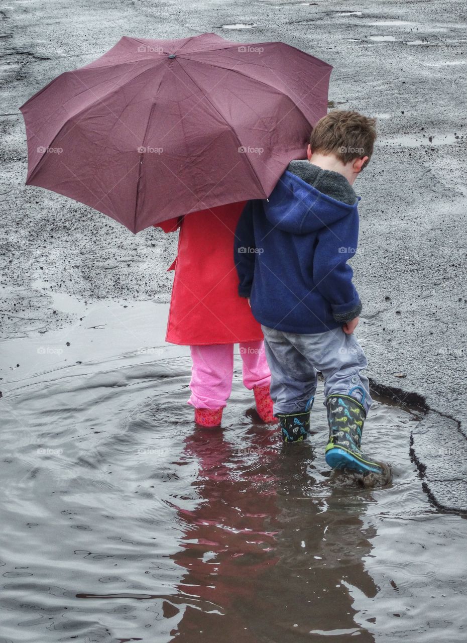 Umbrella Fun. Boy And Girl Sharing An Umbrella In The Rain