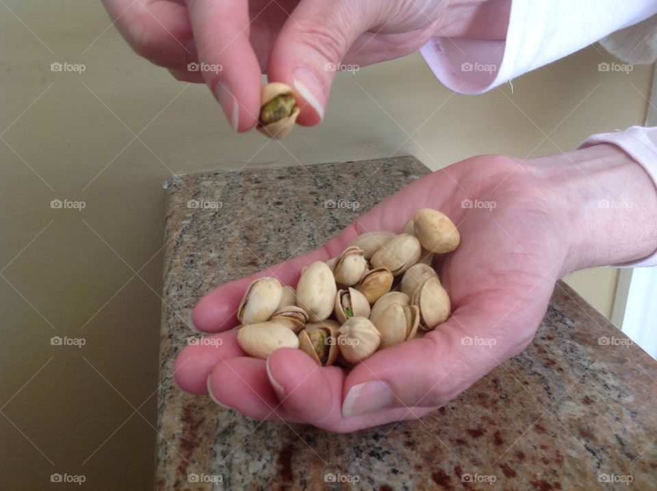 Holding a handful of pistachio nuts.