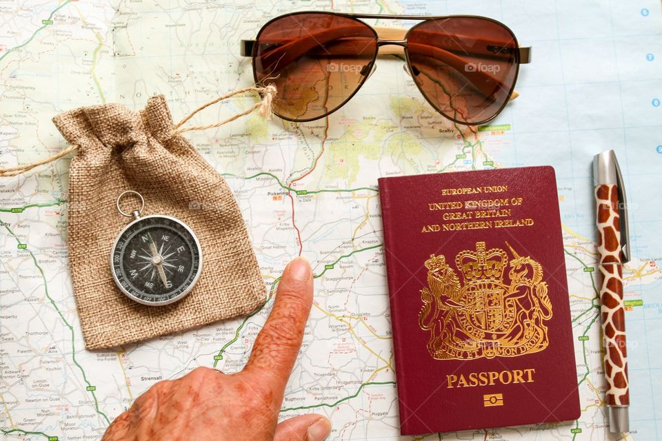 Map compass passport and hand pointing to a map