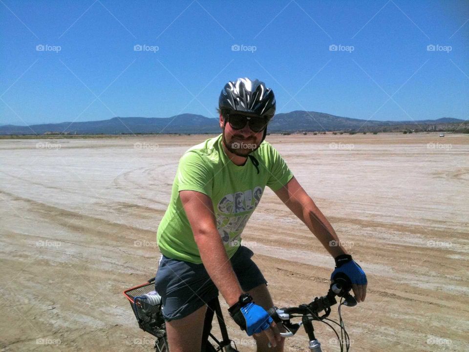 Man biking to the beach in the summer, with mountains in the background