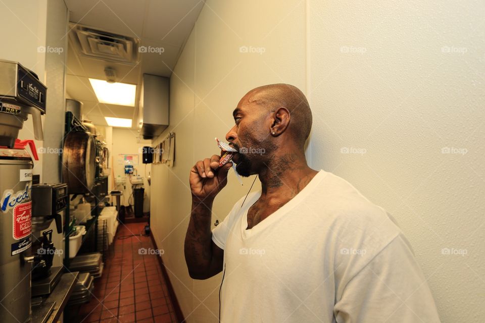 Worker eating some food inside the kitchen in the restaurant 