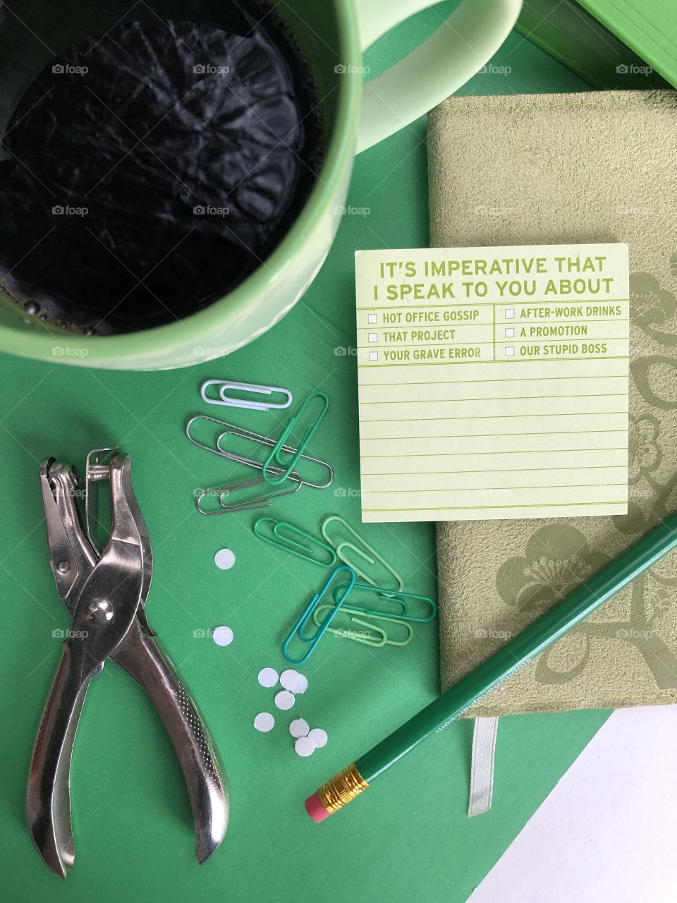 A green and lime themed flat lay with a coffee and a humorous post it note office, supplies, And a coffee