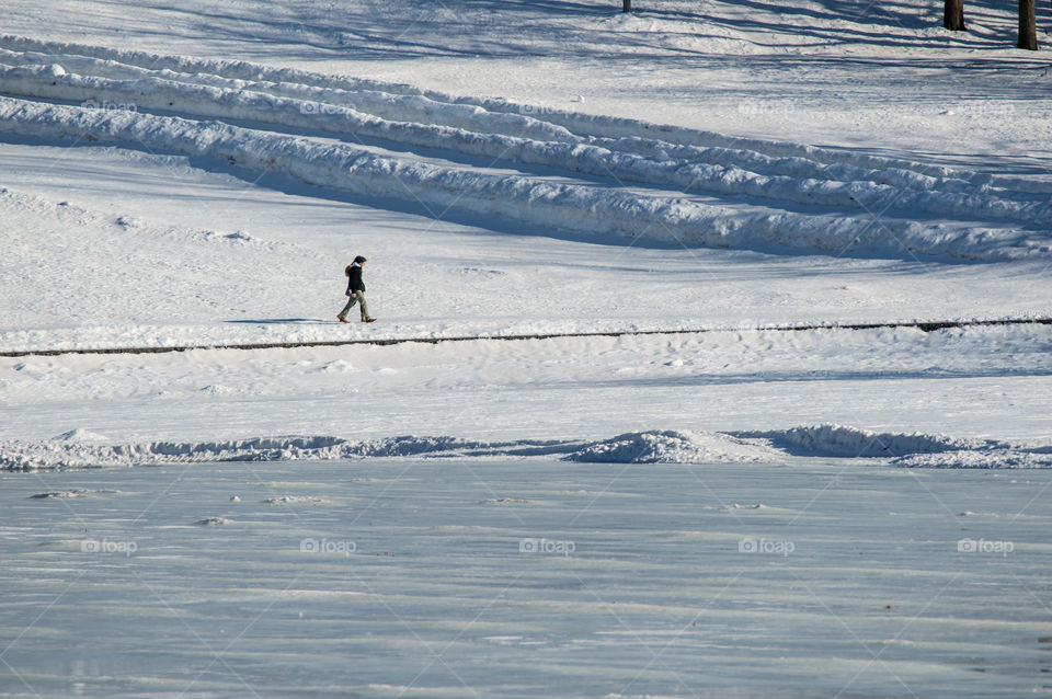 People hiking across vast winter landscape across frozen lake and snow covered mountain winter background 