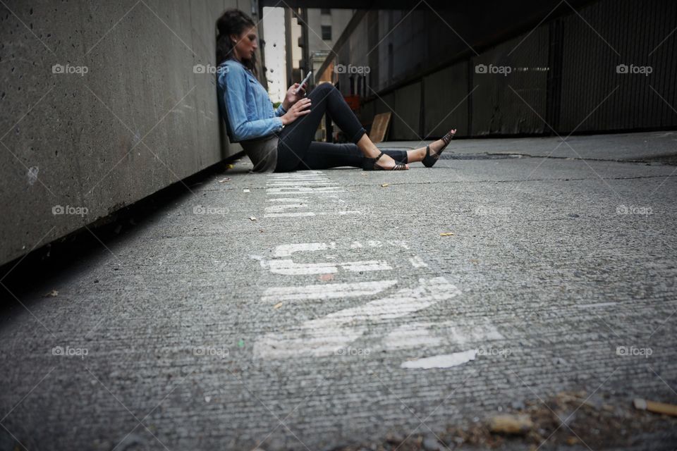 Girl using mobile phone while sitting on the street