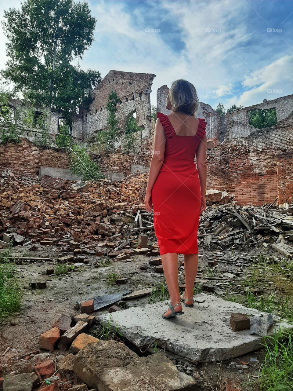 девушка в красном платье на фоне заброшенного здания