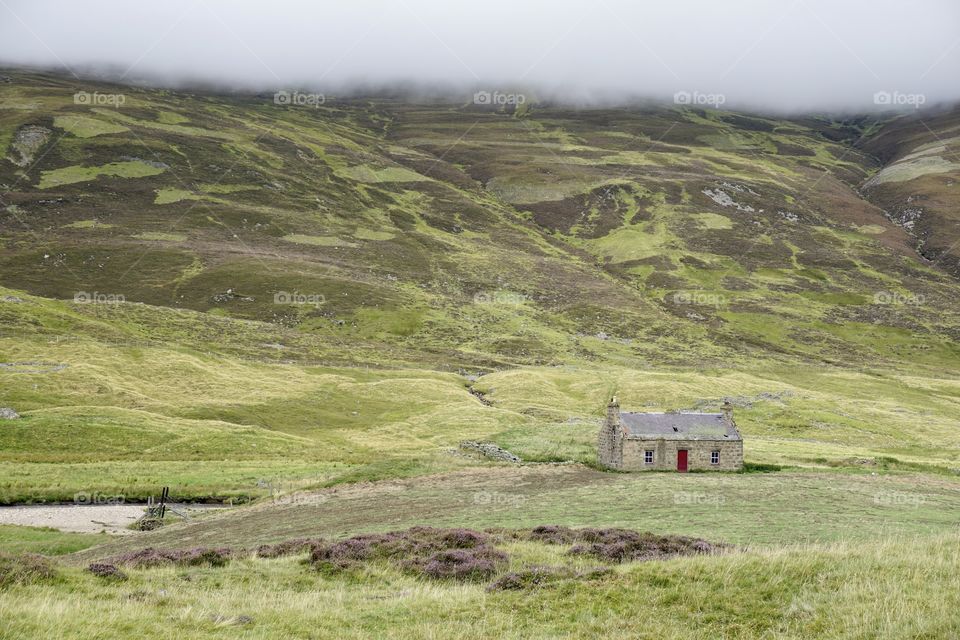 Landscape of a little house in Scotland with mist rolling down the mountain behind it  🏴󠁧󠁢󠁳󠁣󠁴󠁿