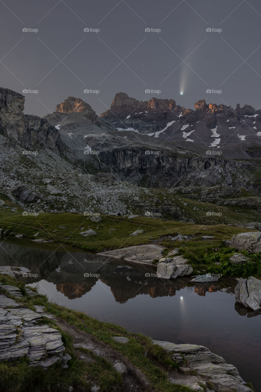 Neowise above mountains reflected in pond.