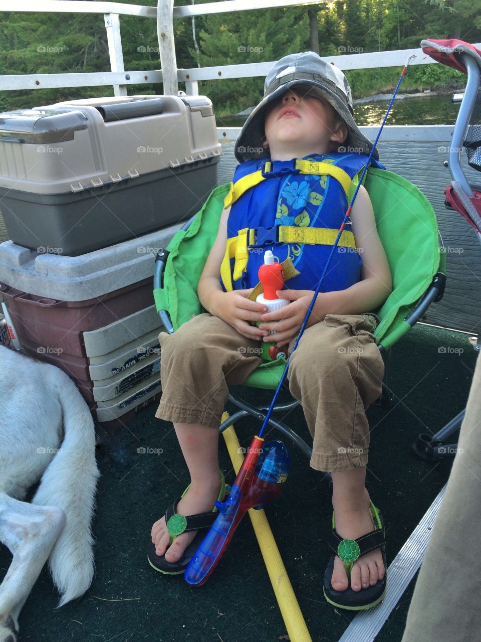 Boy resting on chair with holding fishing rod