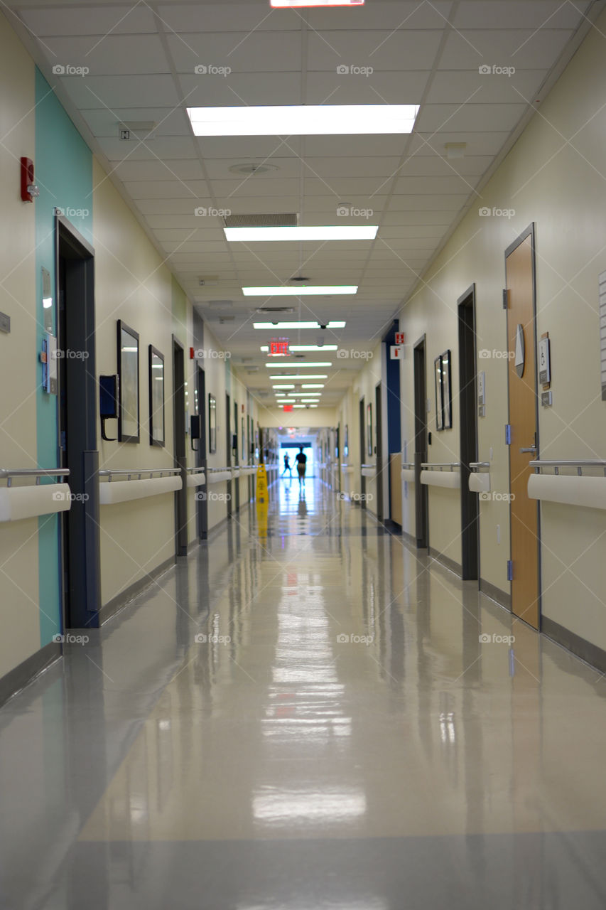 New and clean hospital hallway with doors and lighting, person at the end