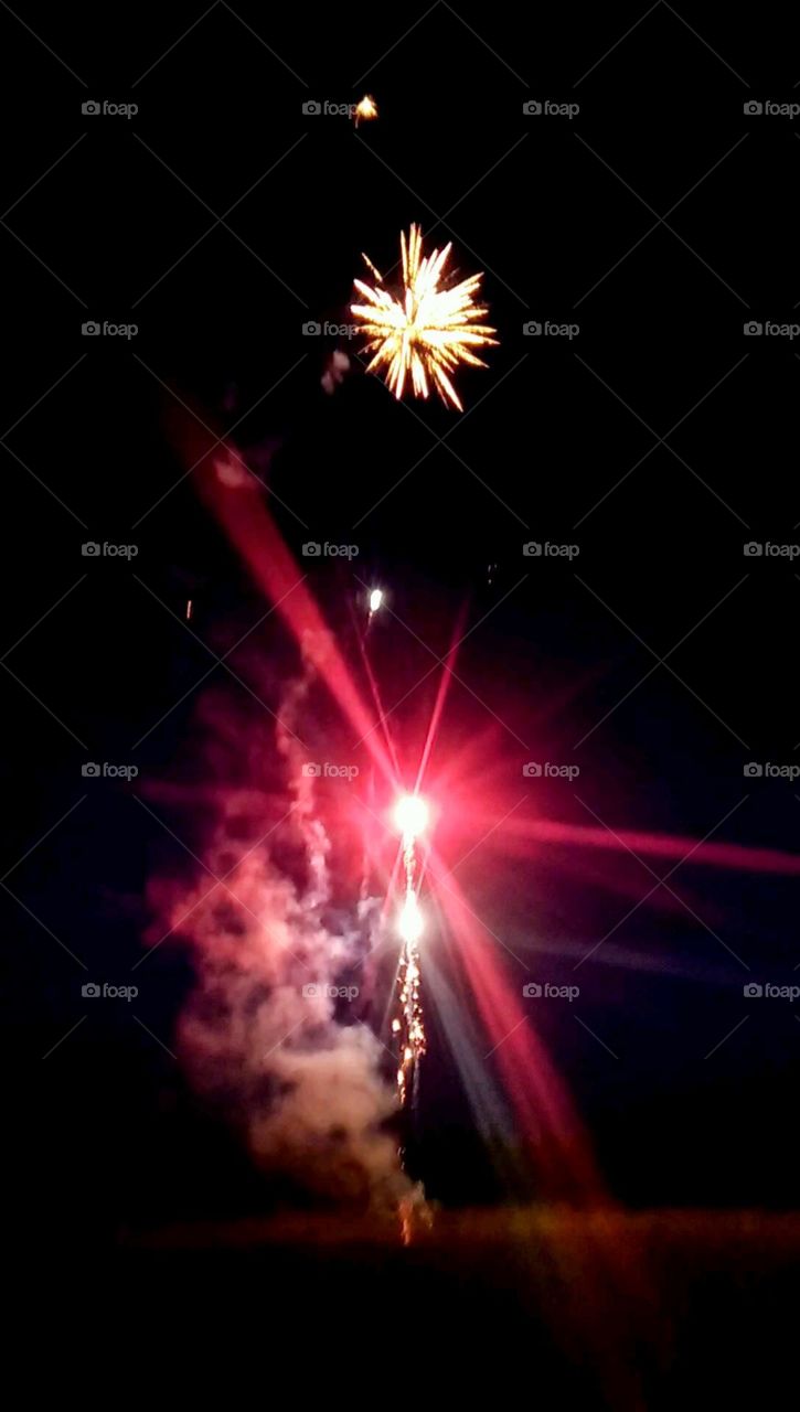 fireworks exploding into the dark sky with bright red and gold sparkles and light